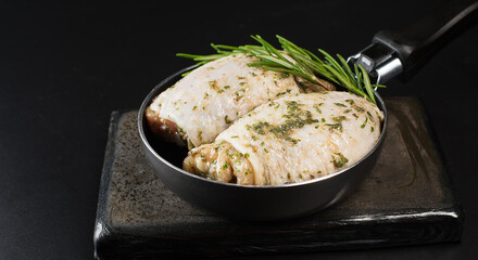 Chicken thighs with spices, garlic.Close-up, top view.Raw chicken thighs marinated in herbal sauce on a dark background with fresh rosemary, spices.Copy space.Raw Meat Chicken.