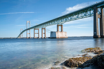 Tranquil seascape with the view of Claiborne Pell Newport Bridge and smooth water flowing under the bridge, long exposure photography.