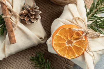 Zero waste christmas concept. Packed in natural fabric gifts and decorations from natural materials on gray table, closeup, top view