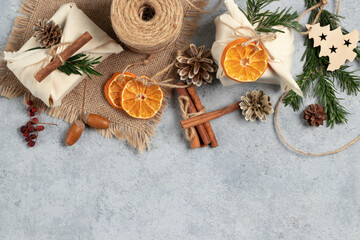 Zero waste christmas concept. Packed in natural fabric gifts and decorations from natural materials on gray table, top view, copy space