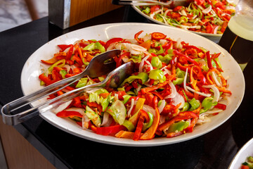 A mix of cucumbers and bell peppers is on a large plate.