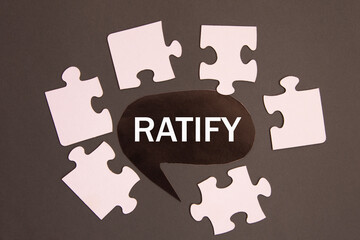 RATIFY - word on a black note against the background of white puzzles