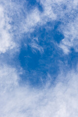 Vertical blue sky background with white clouds.