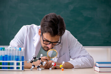 Young male chemist in front of blackboard