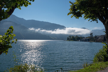 Fototapeta na wymiar Scenic panoramic view of classic alpine mountain scenery with idyllic blue lake and fog above water surface, Zell am See, Salzburg Land, Austria