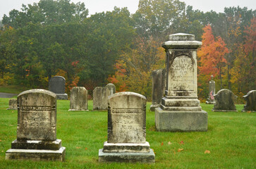 Fototapeta na wymiar Old gravestones in a cemetery on a rainy autumn day