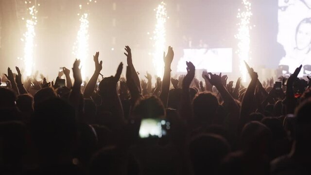 Crowd cheering on a music festival. Hands in the air. Colorful illuminations and smoke