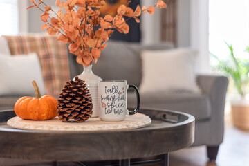 Coffee table with a mug that says Talk Pumpkin Spice to Me in a stylish living room decorated for fall - 465149727