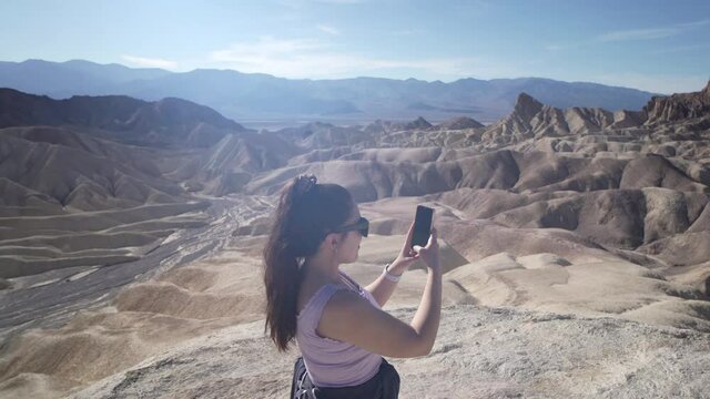 Young Woman Taking Pictures With Her Smartphone While Traveling in the Desert