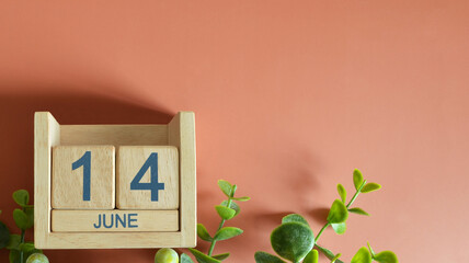 June 14, Date design with calendar cube and leaf on orange background.