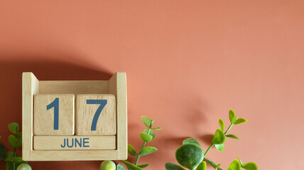 June 17, Date design with calendar cube and leaf on orange background.