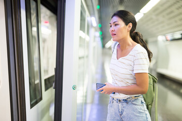 Asian woman getting on train that just arrived to subway station.