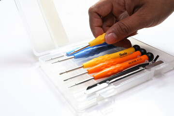 Screwdriver kit. Man's hand taking a screwdriver out of the case on white background.
