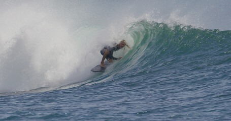 Surfer surfing riding a small barrel tube