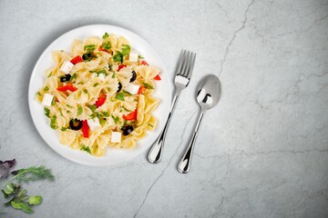 Pasta with cherry tomatoes, cheese and basil on a light plate