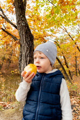 Child stands in nature and eats an apple. Healthy food concept.