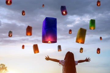 Asian child girls are releasing lanterns to blessings from the Holy for happiness on the important Buddhist holy day it is Buddhist Lent days. Child girls stand and look with excitement © Kampan