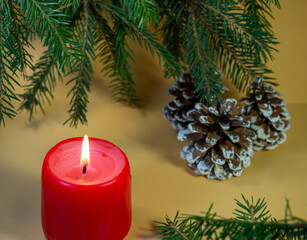 New Year's card, decorations. Candle, cones and fir branches on a beige background. New Year. Christmas