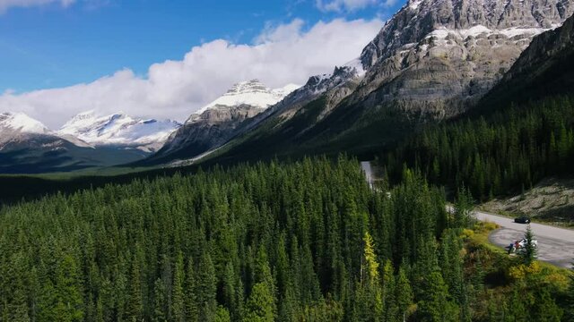 Ariel View of Road in Mountains and Forest with green Pine Woods in Banff National Park. Scenic view on Sunny day in Rocky Mountains in Canada. Road trip.