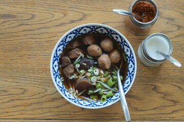 Top view rice noodle with pork meatballs on wood table.