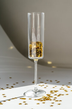 Champagne glass with golden confetti and sparkler on a white background.