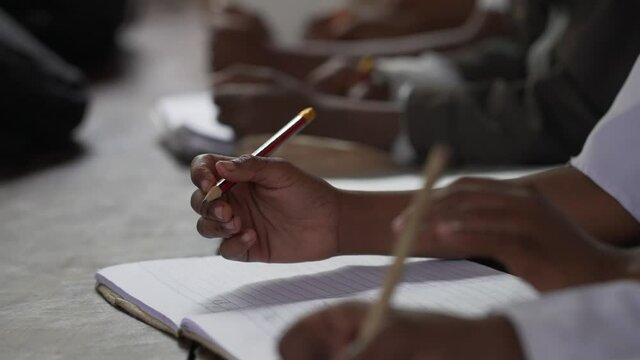 Muslim arabic african kids at school writing in her notebook. Education in the islamic countries. Close up shot of hands with a pencil. Education in three world poor countries. Africa 4K