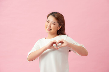 young woman making a heart gesture with her fingers in front of her chest