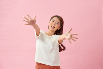 Happy young woman posing in front of a pink background