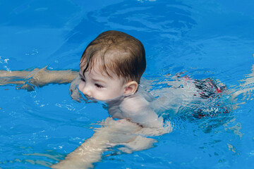 Fototapeta na wymiar little child learns to swim in the pool with an instructor