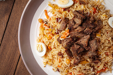 Uzbek national dish pilaf plov with rice and meat on wooden background