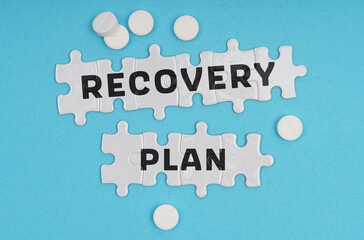 Fototapeta premium On a blue background pills and puzzles with the inscription - RECOVERY PLAN