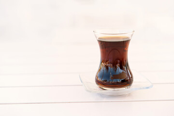 Turkish tea served in tulip-shaped glass on rustic table. Turkish tea in traditional glass cup. Turkish traditional hot drink