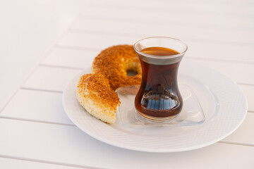 Crispy Turkish traditional bagel, simit with sesame and glass of turkish black tea, turkish breakfast pastry concept. Turkish tea in traditional glass cup. 