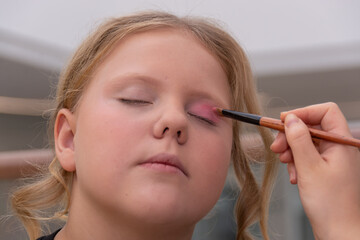 A makeup artist makes makeup for a child. 