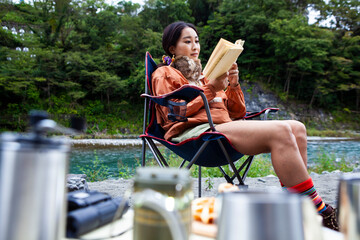 川辺でソロキャンプをする女性／読書を楽しむ