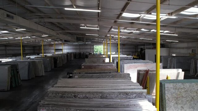 View Inside A Slab Warehouse And Showroom With Stacks Of Granite And Marble Slabs On Display. drone shot
