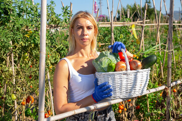 Fototapeta premium Portrait of young female amateur farmer with harvested vegetables and greens in garden