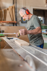 Worker measuring a wooden step on a sliding table saw