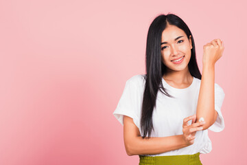 Portrait of Asian beautiful young woman applying lotion cosmetic moisturizer cream on her elbow skin, studio shot isolated on pink background, Healthcare medical and hygiene skin body care concept