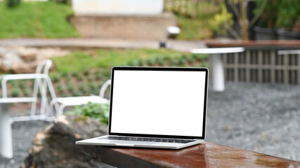 Mock up laptop computer with Wie display on wooden table in the garden. - obrazy, fototapety, plakaty