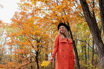 Young girl with blond hair walks in the autumn forest. Wellness concept.