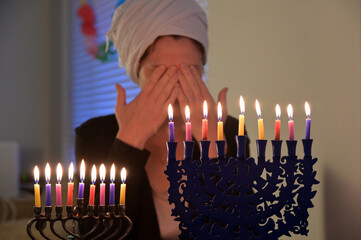 Jewish woman blessing on colourful candles on candelabrum on the eight day of Hanukkah Jewish...