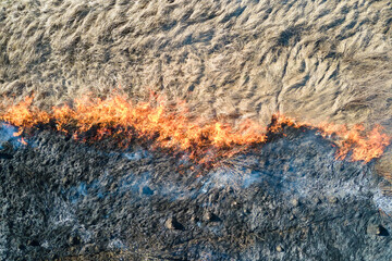 Aerial view of grassland field burning with red fire during dry season. Natural disaster and...