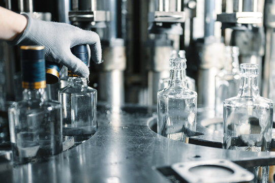 Worker Puts Plastic Cap On Bottle Of Luxury Vodka In Shop