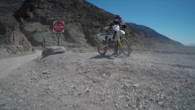 Desert moto rider, motocross, motorcycle going through desert canyon, trick ride, wheelie, mad max style, cb650 pro rider, super fast and fun, exciting and wild.