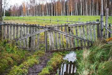 Old wooden gate in an animal pasture on an autumn day.