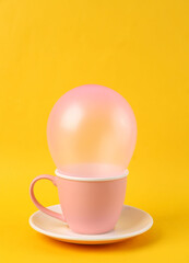 Pink balloon in cup on bright yellow background