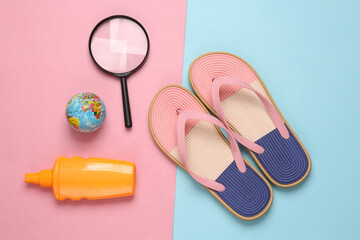 Colored flip flops with beach accessories on blue-pink pastel background. Beach vacation concept. Flat lay