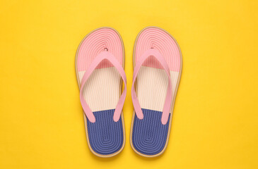 Colored flip flops on yellow background