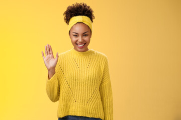 Cute timid friendly young girl wanna find new friends look pleasant smiling charmingly gladly waving hand hello hi gesture say welcome greeting heartwarming introduction herself, yellow background - obrazy, fototapety, plakaty